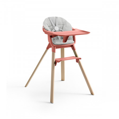 Cojín trona Clikk de Stokke, trona de color soral soleado y patas de madera.