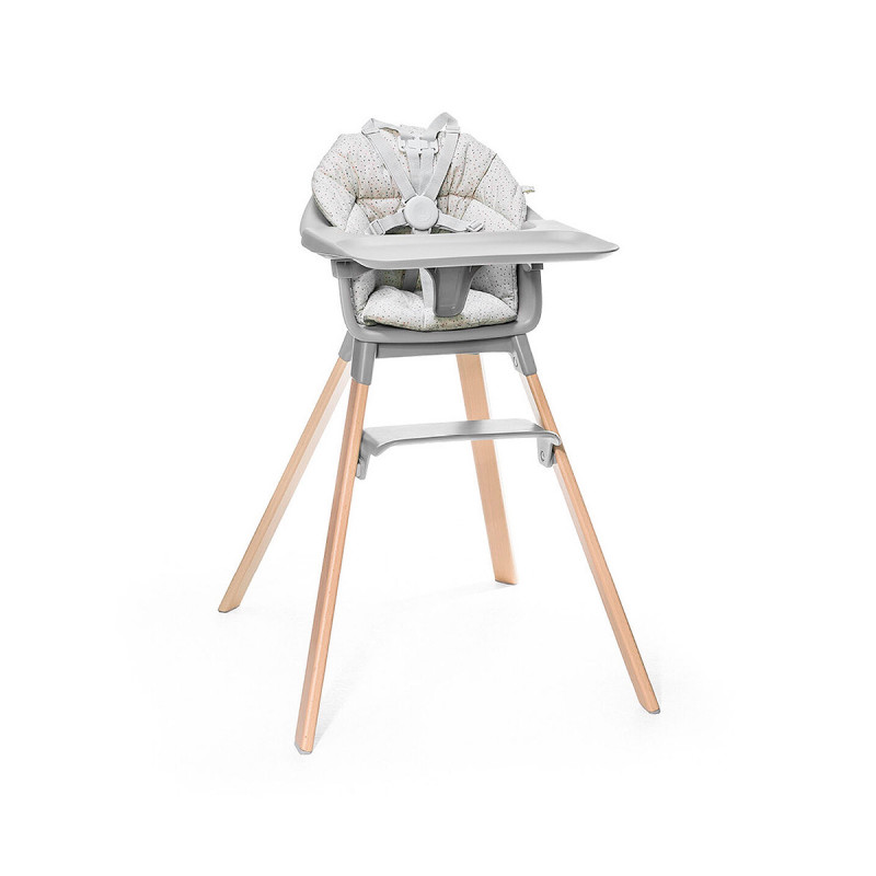 Cojín trona Clikk de Stokke, trona de color gris y patas de madera.