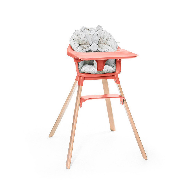 Cojín trona Clikk de Stokke, trona de color soral soleado y patas de madera.