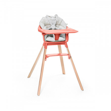 Cojín trona Clikk de Stokke, trona de color soral soleado y patas de madera.