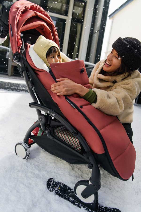 imagen del saco de invierno Yoyo de Stokke en color berry y los skies montados en las ruedas