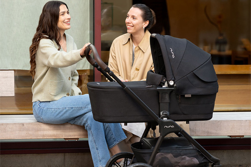 amigas hablando y madre sujetando el capazo Lytl LX de Nuna
