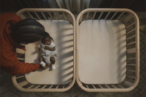 madre acostando a su bebé en la minicuna Stokke Nighti MINI