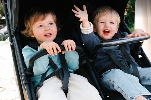 hermanos apoyados en reposabrazos del carrito gemelar minu duo de uppababy